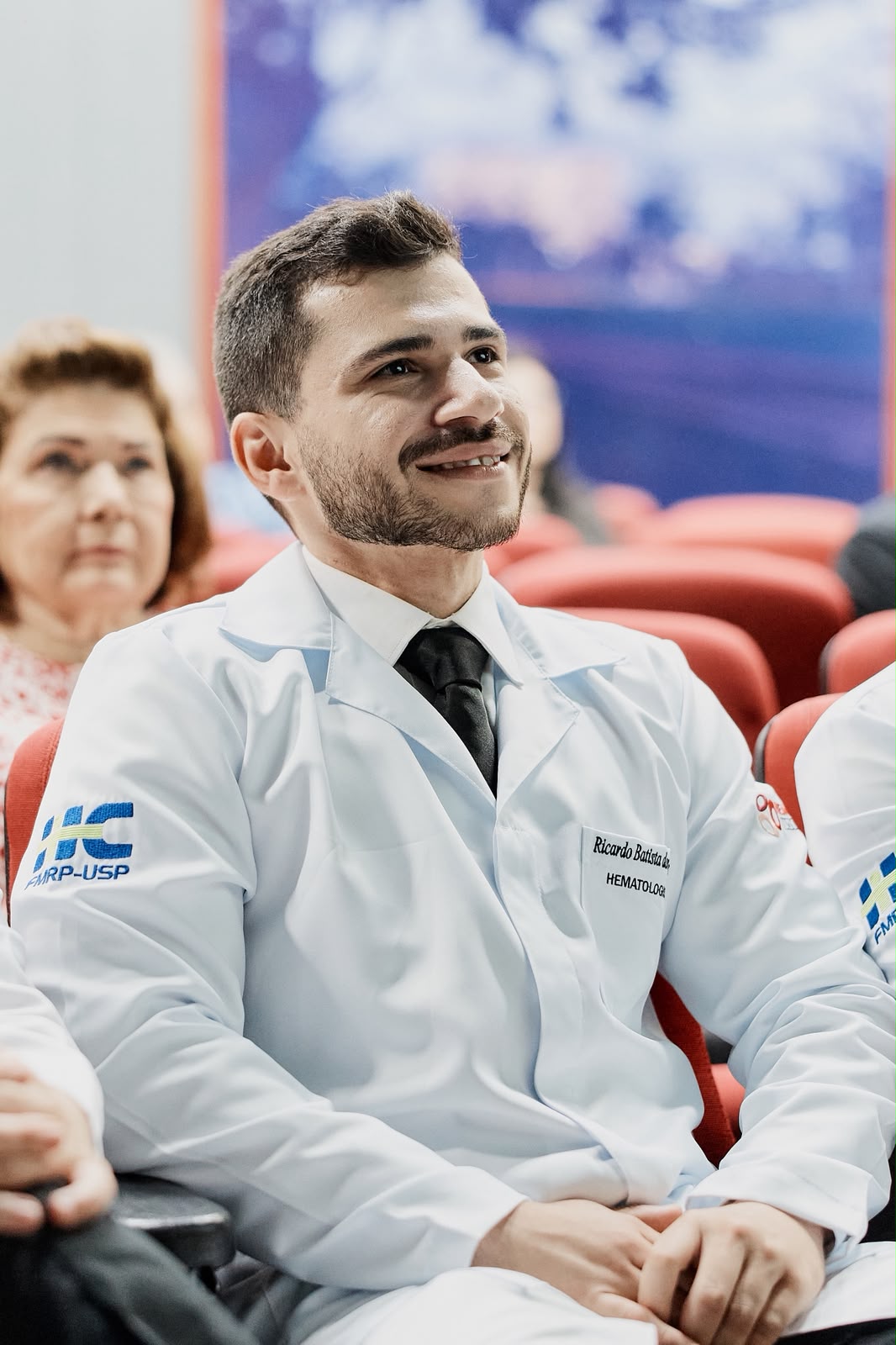 Dr. Ricardo Batista sorrindo durante cerimônia de conclusão da residência em Hematologia.